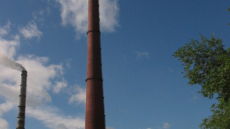 Industrial smokestacks emitting vapour into a clear sky