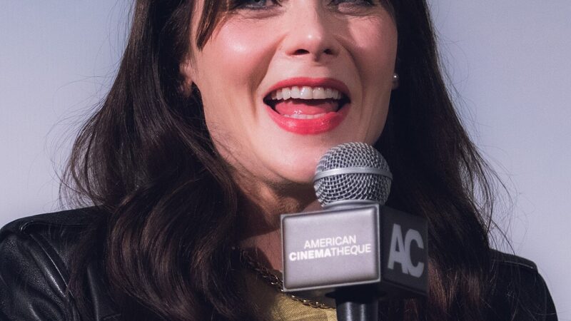 Zooey Deschanel speaking at a microphone at an event